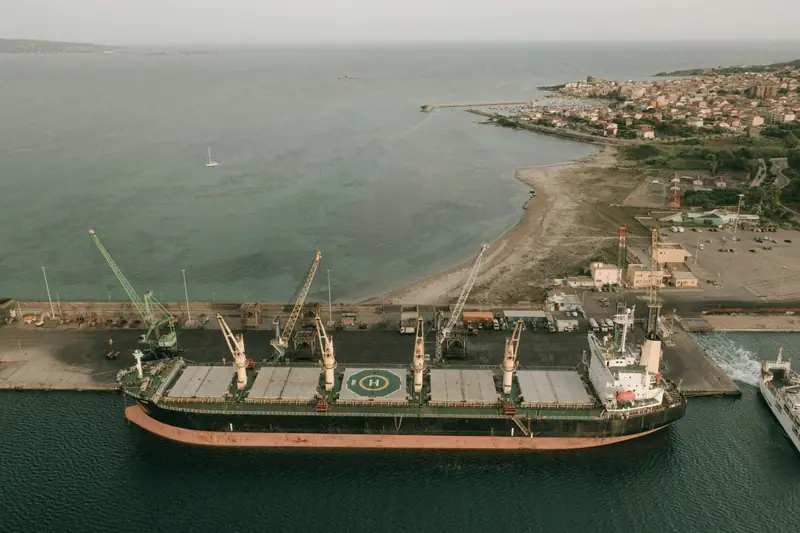A bulk carrier alongside a quay with cranes, seen from the air